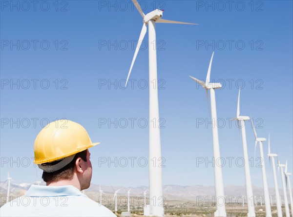 USA, California, Palm Springs, Coachella Valley, San Gorgonio Pass, Man in hard hat looking at wind turbines. Photo : Jamie Grill Photography