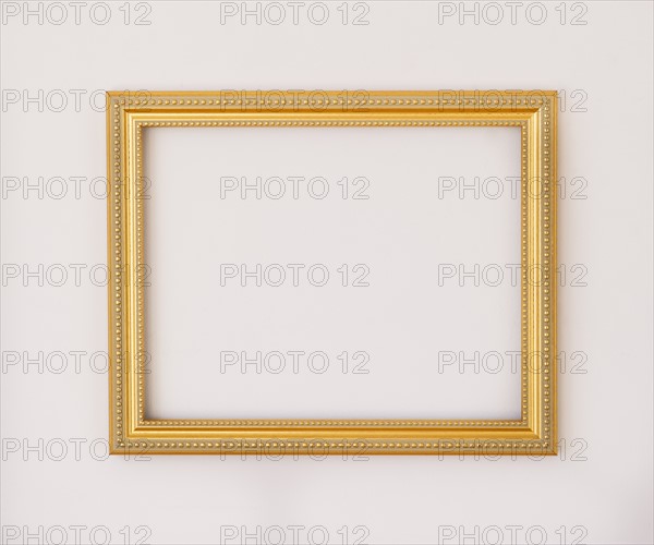 Studio shot of golden picture frame on white background. Photo : Daniel Grill