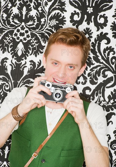 Studio portrait of young man using still camera. Photo : Daniel Grill