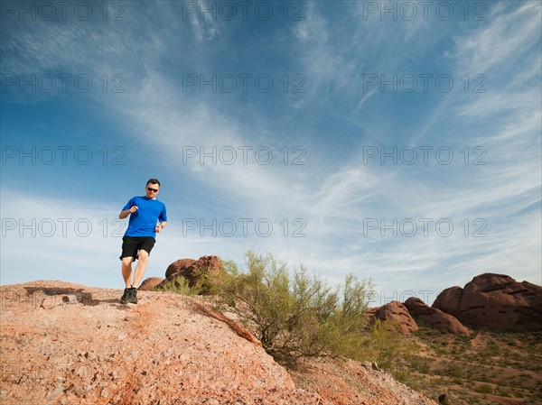 USA, Arizona, Phoenix, Mid adult man jogging on desert.