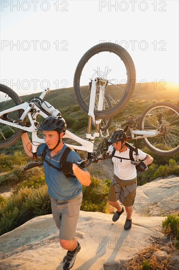 USA, California, Laguna Beach, Two men carrying bikes up hill.
