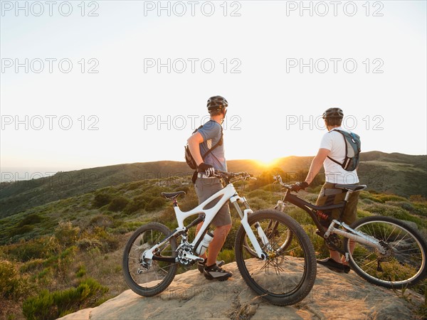 USA, California, Laguna Beach, Two bikers on hill looking at view.