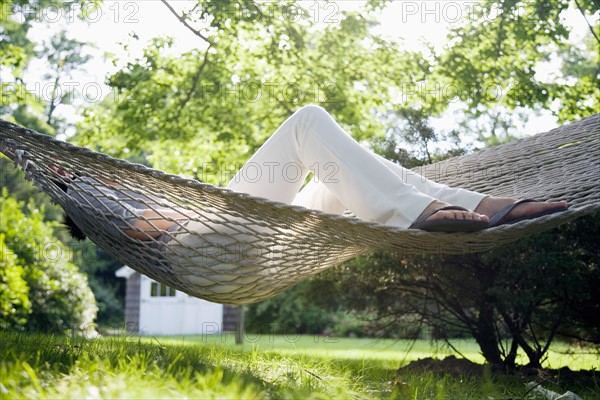 USA, New York State, Long Island, woman relaxing in hammock. Photo : Maisie Paterson