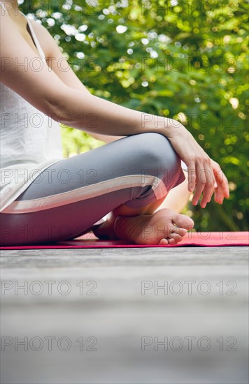 Woman sitting in yoga position in garden. Photo : Maisie Paterson