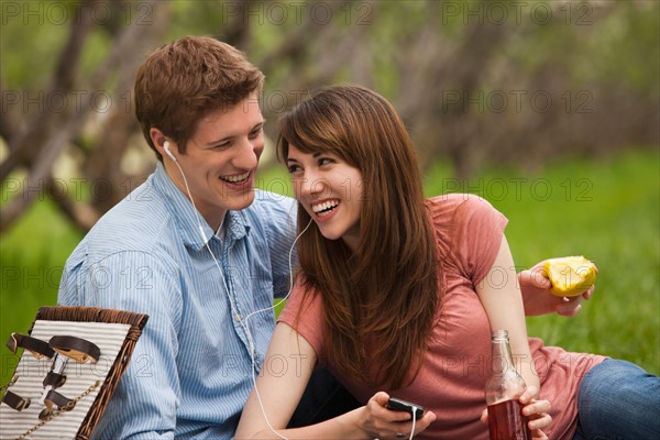 Young couple with mp3 player in orchard. Photo : Mike Kemp