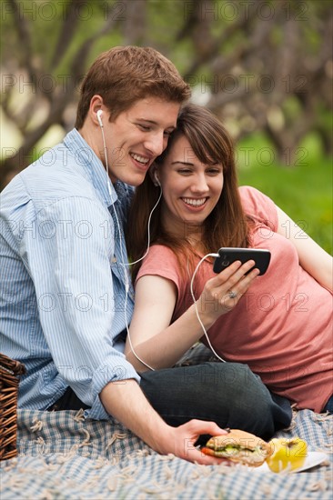 Young couple with mp3 player in orchard. Photo : Mike Kemp