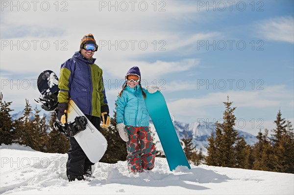 USA, Colorado, Telluride, Father and daughter (10-11) posing with snowboards in winter scenery. Photo : db2stock
