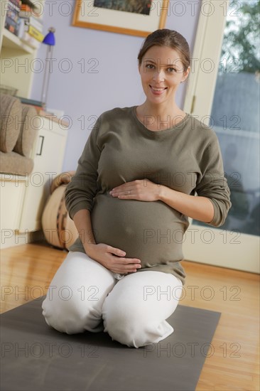 Portrait of expectant mother sitting on exercise mat. Photo : Rob Lewine