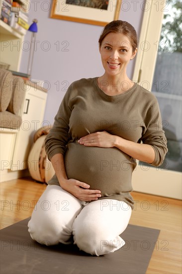 Portrait of expectant mother sitting on exercise mat. Photo : Rob Lewine