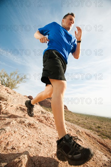 USA, Arizona, Phoenix, Mid adult man jogging on desert.