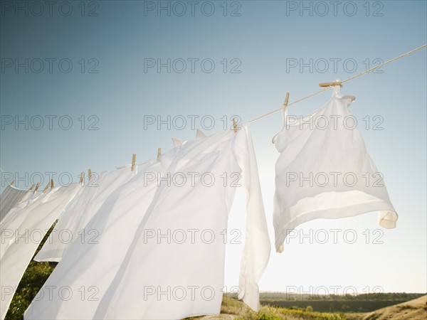 Laundry hanging on clothesline against blue sky.