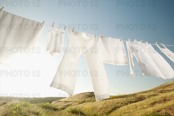 Laundry hanging on clothesline against blue sky.