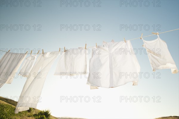 Laundry hanging on clothesline against blue sky.