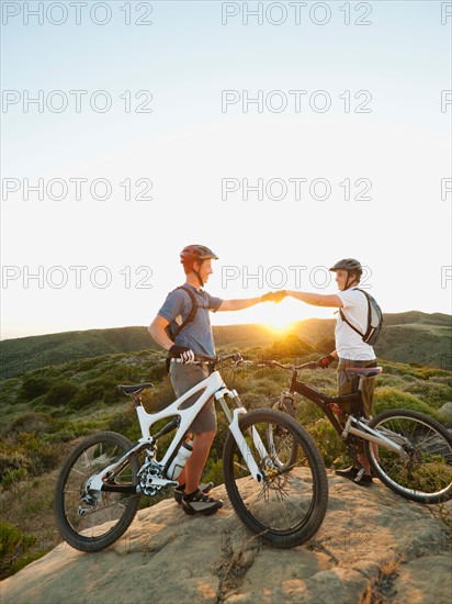 USA, California, Laguna Beach, Two bikers on hill doing fist bump.