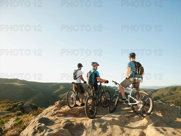 USA, California, Laguna Beach, Two bikers on hill looking at view.