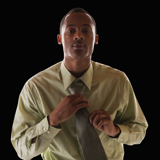 Businessman tying tie. Photo : Mike Kemp