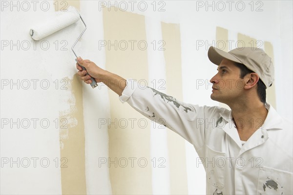 Man painting wall white.