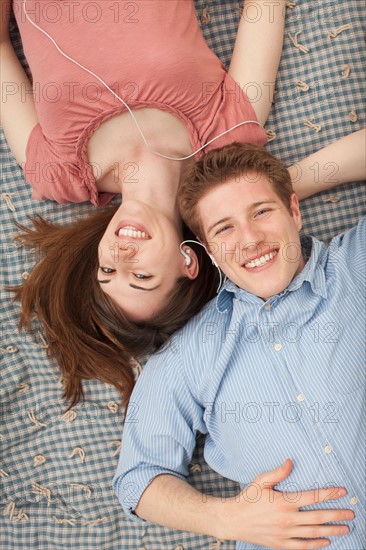 Young couple with mp3 player lying on blanket. Photo : Mike Kemp