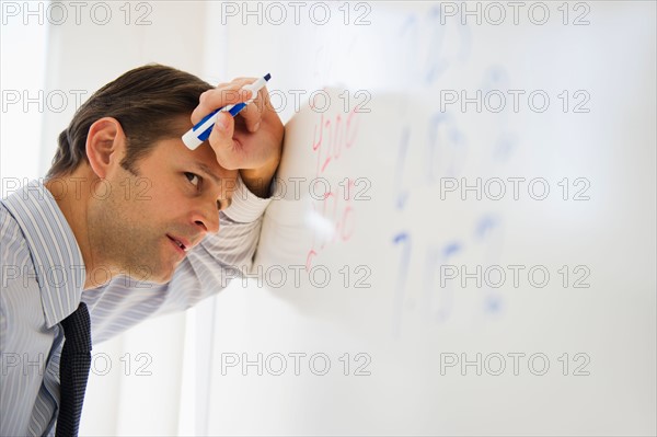 Exhausted man leaning against whiteboard.