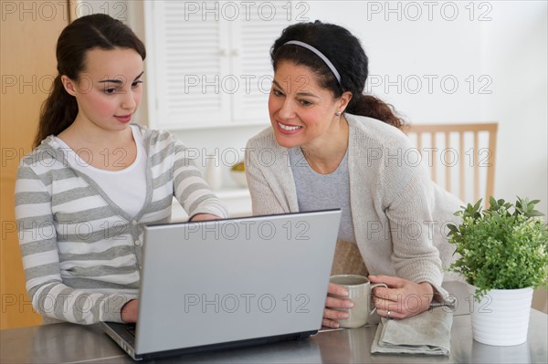 Mother with teenage daughter (14-15) working on laptop.