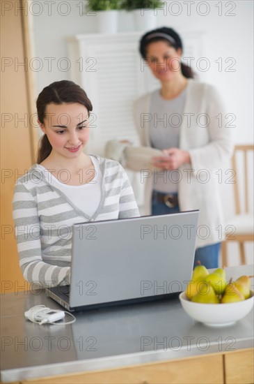 Mother with teenage daughter (14-15) working on laptop.