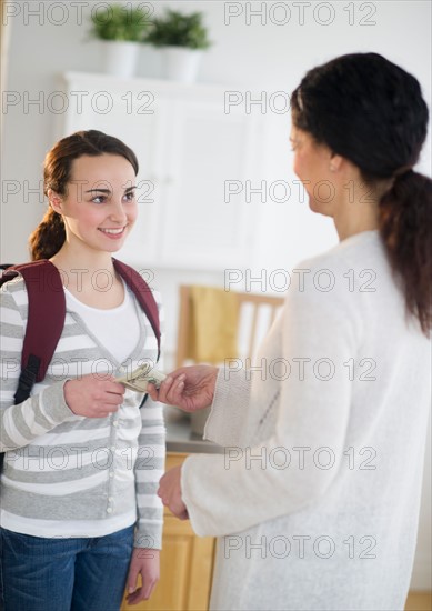 Mother giving money to teenage daughter (14-15).