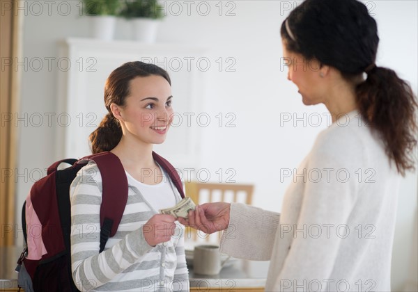 Mother giving money to teenage daughter (14-15).