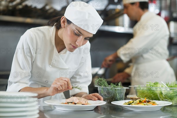 Chef and cook preparing food in commercial kitchen.