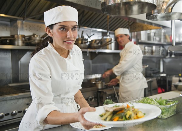 Chef and cook preparing food in commercial kitchen.