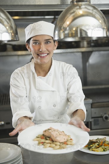 Female cook showing food on plate.
