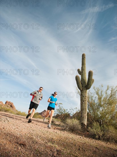 USA, Arizona, Phoenix, Mid adult man and young woman jogging on desert.