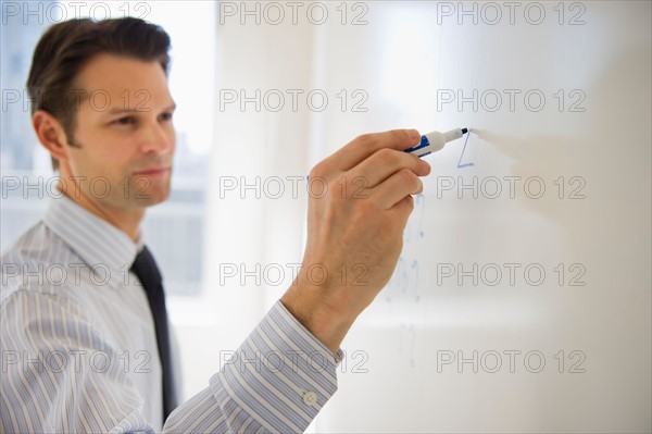 Businessman writing on whiteboard.