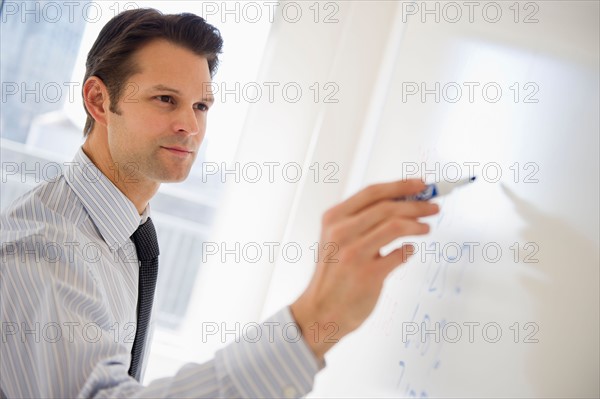 Businessman writing on whiteboard.