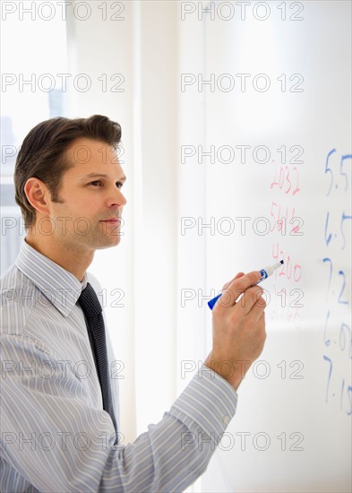 Businessman writing on whiteboard.