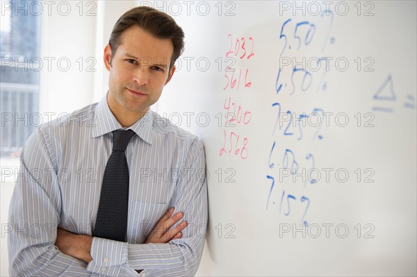 Portrait of businessman leaning against whiteboard.