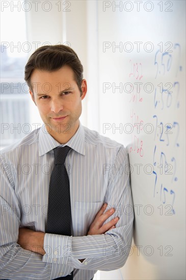 Portrait of businessman leaning against whiteboard.