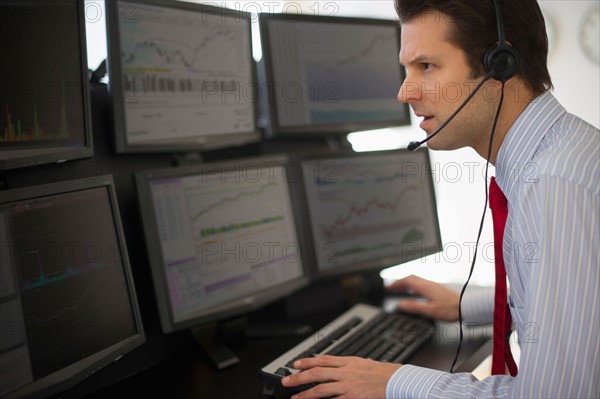 Financial worker analyzing data displayed on computer screen.