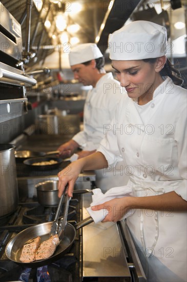 Chef and cook preparing food in commercial kitchen.