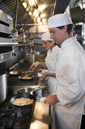 Chef and cook preparing food in commercial kitchen.