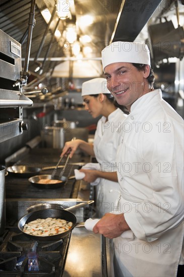 Chef and cook preparing food in commercial kitchen.