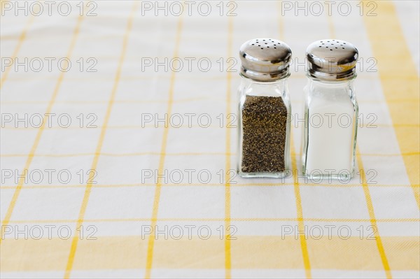 Salt and pepper shakers on checked tablecloth.