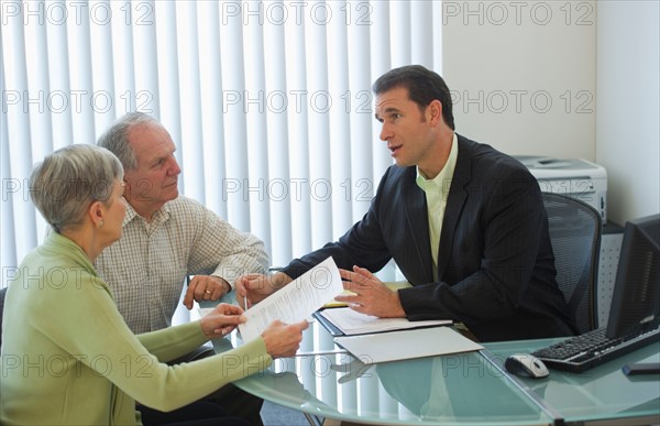 Senior couple talking to man in office.