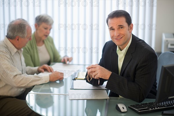 Senior couple talking to man in office.