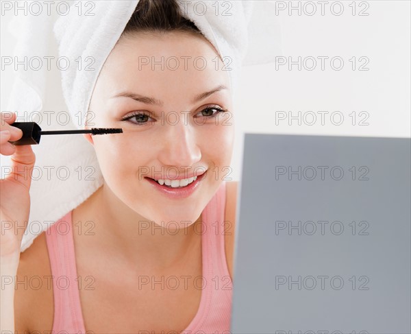 Young woman applying mascara. Photo : Jamie Grill Photography