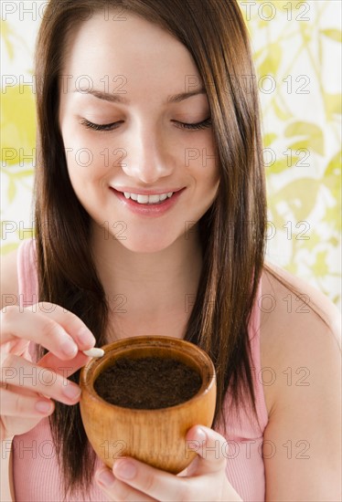 Smiling young woman holding pot with soil and bean. Photo : Jamie Grill Photography