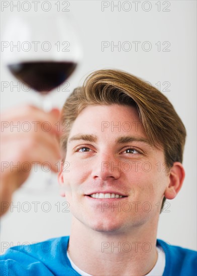 Young man examining red wine. Photo : Daniel Grill