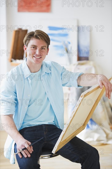 Portrait of young man painting picture in studio. Photo : Daniel Grill