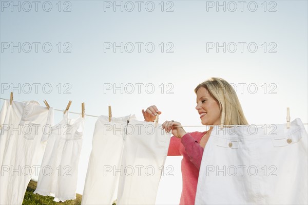 Woman hanging laundry on clothesline .