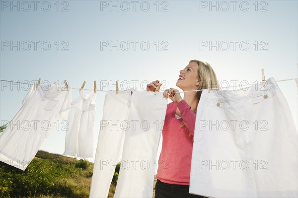 Woman hanging laundry on clothesline .