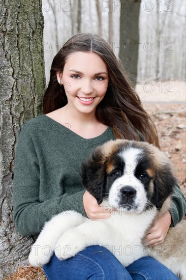 USA, New Jersey, Califon, Teenage girl (16-17) sitting with Saint Bernard puppy on laps, portrait. Photo : Pauline St.Denis